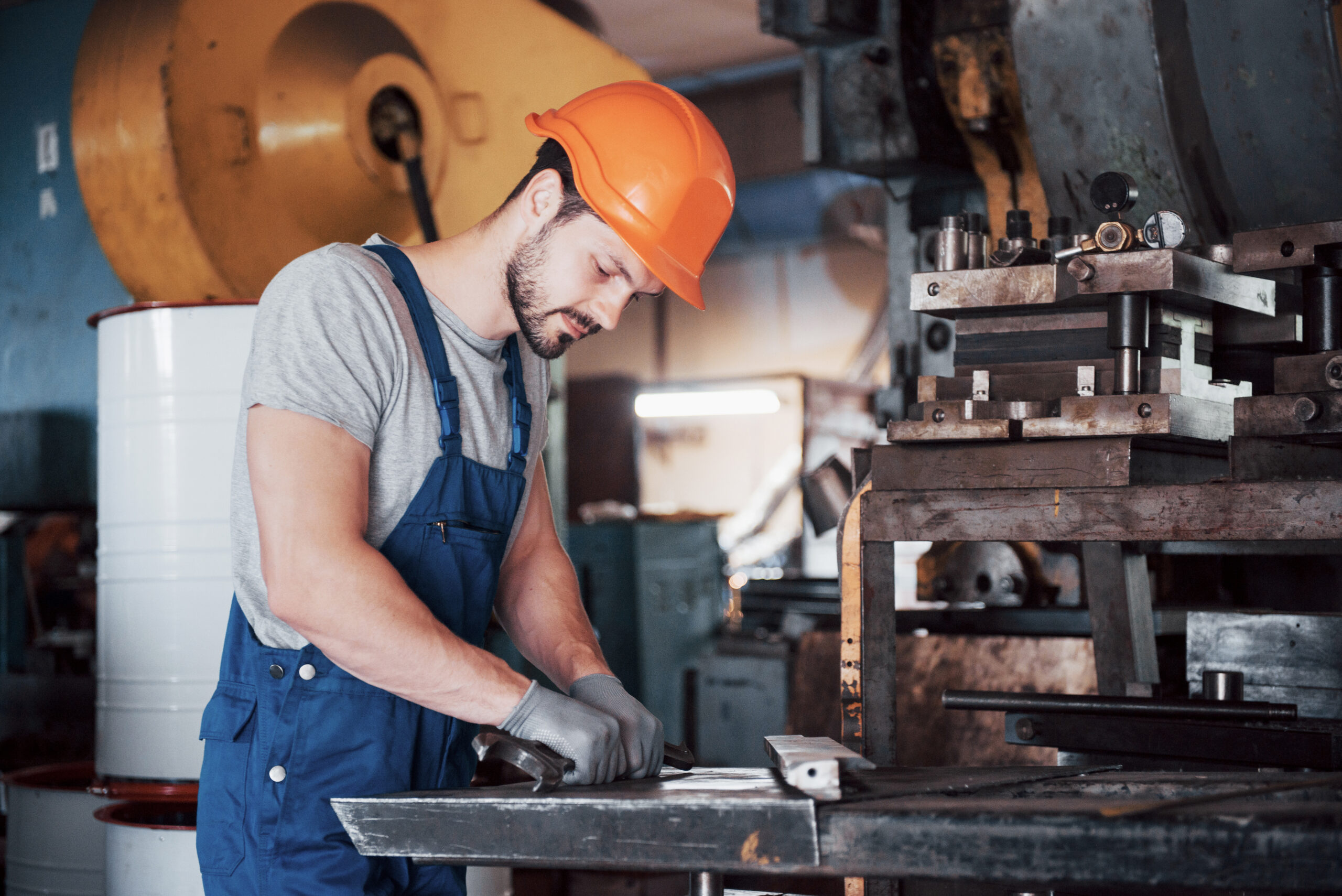 Portrait of a young worker in a hard hat at a large waste recycling factory. The engineer monitors the work of machines and other equipment.